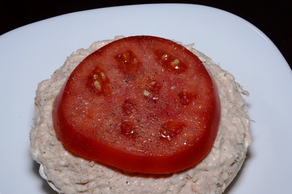 an open face bagel with cream cheese, tuna and tomato