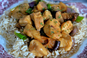 Plate containing chicken with black mushrooms on a bed of brown basmati rice