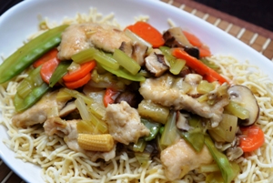 A dish containing Chinese chicken and pineapple stir fry on a bed of Chinese noodles