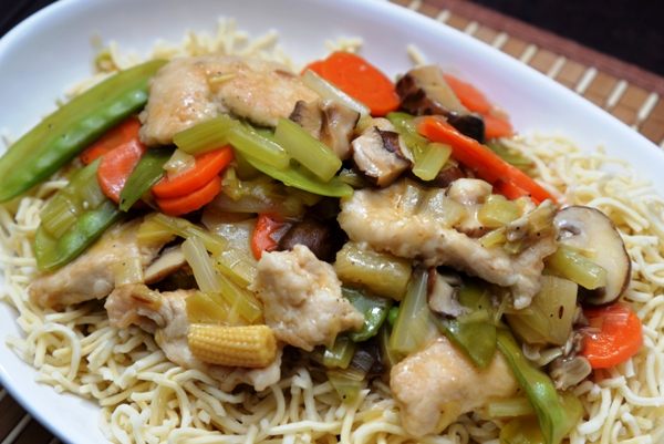 A dish containing Chinese chicken and pineapple stir fry on a bed of Chinese noodles