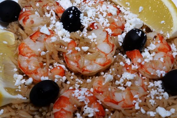 Plate of shrimp pilaf, showing rice, shrimps, olives and lemon wedges