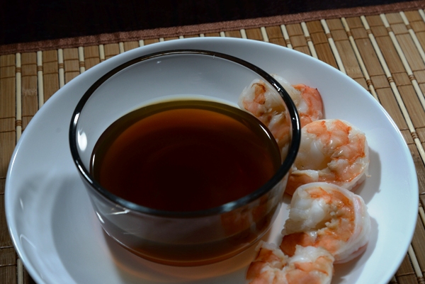 shrimp stock in a bowl on a plate with cooked shrimp